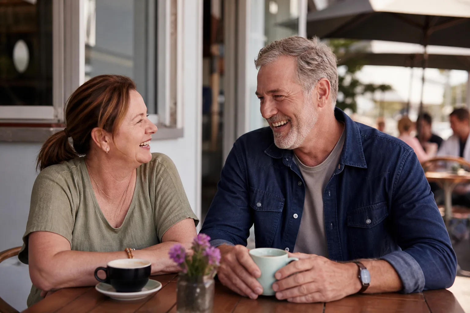 Two mature adults talking over coffee beside Wellington's waterfront